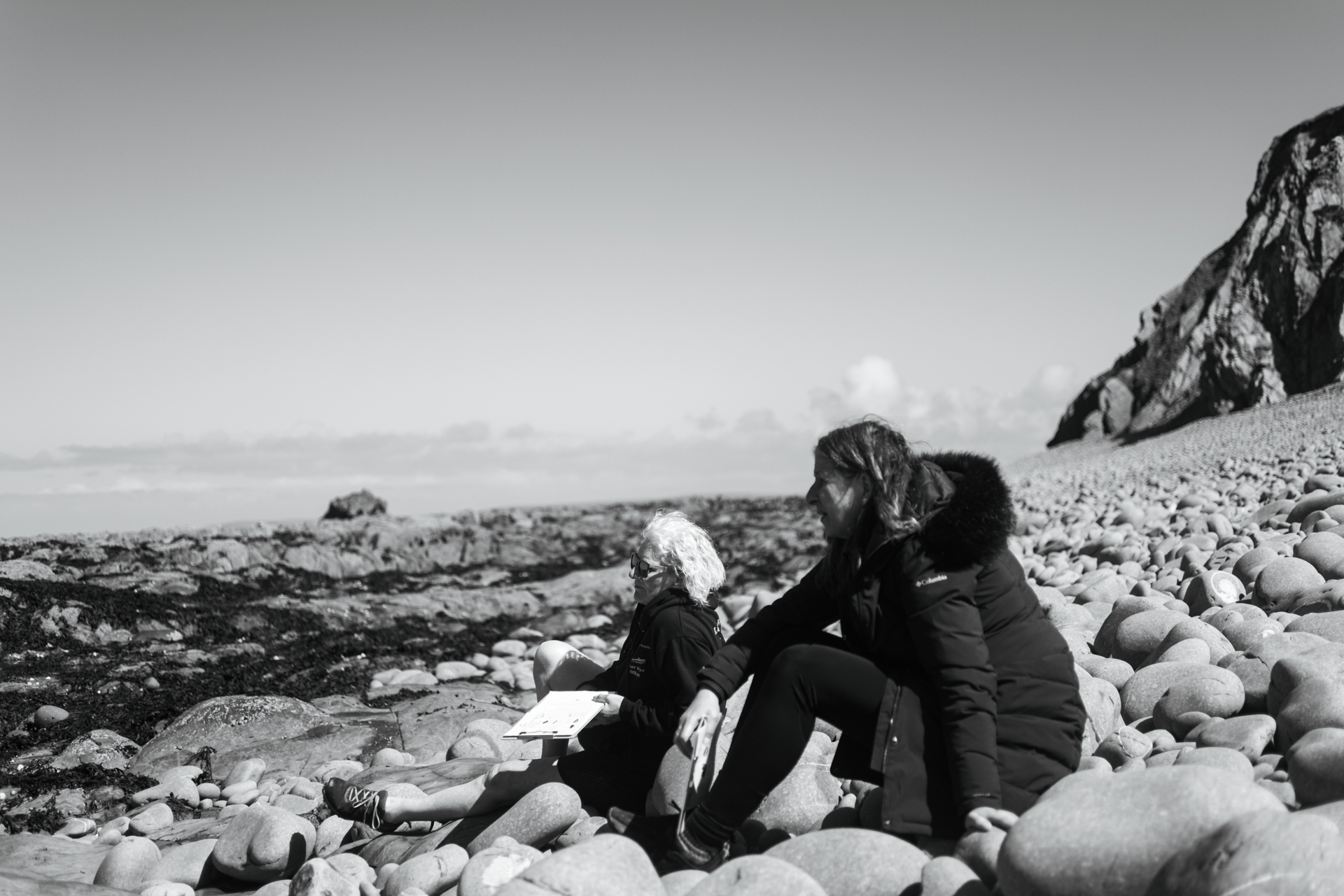 Two women sit near each other and peacefully look at the scenery around them.